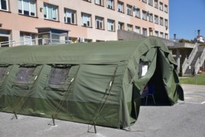 Namiot na tle wejścia do szpitala od strony lądowiska