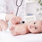 niemowlę w pieluszce badane przez lekarza stetoskopem