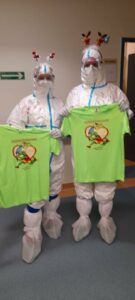 dwoje fizjoterapeutów w kombinezonach ochronnych z koszulkami otrzymanymi dla pacjentów od biegaczy