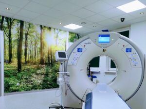 widok na aparat do tomografii komputerowej w pracowni z fototapeta z drzewami na ścianie
