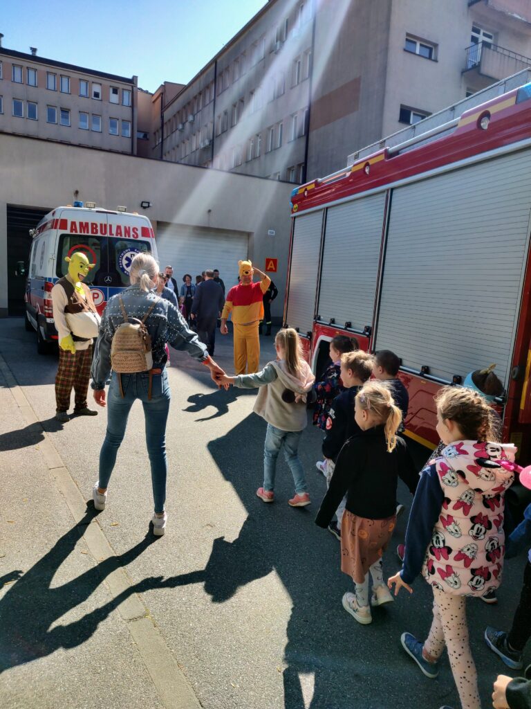 grupa przedszkolaków wita się z puchatkiem i shrekiem przed garażami zrm