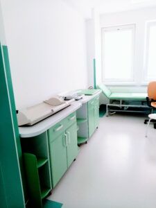 wnętrze gabinetu lekarskiego w poradni dziecięcej z szafkami na wagę, miejscem do badania niemowląt i kozetka dla pacjenta
