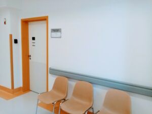 widok na wejście do gabinetu lekarskiego i krzesła w poczekalni POZ
